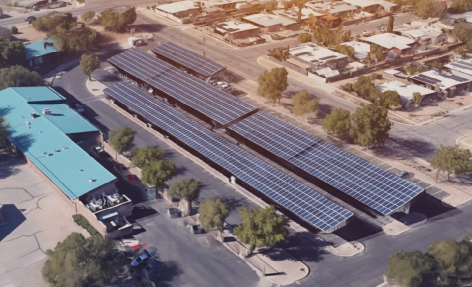 Aerial view of a parking lot with rows of carports covered in solar panels, located next to buildings with teal roofs and surrounded by trees. Perfect setting for commercial EV charging or utilizing commercial solar PPA solutions.